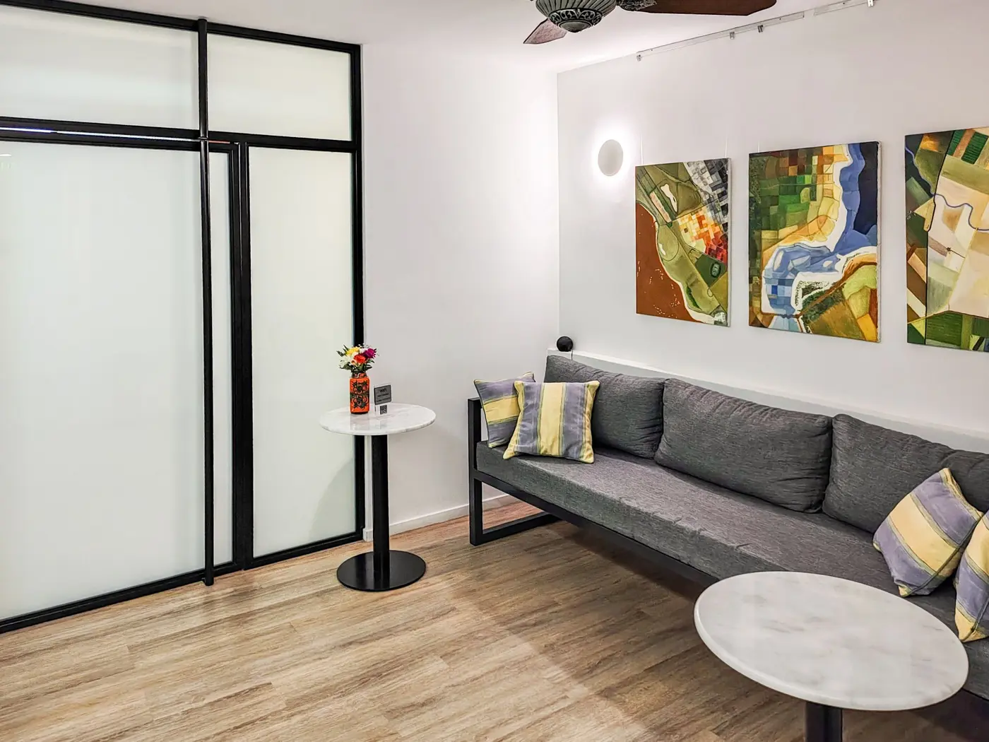 Sala de espera con sillón gris y cuadros